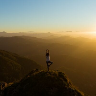 woman stretching on mountain top during sunrise