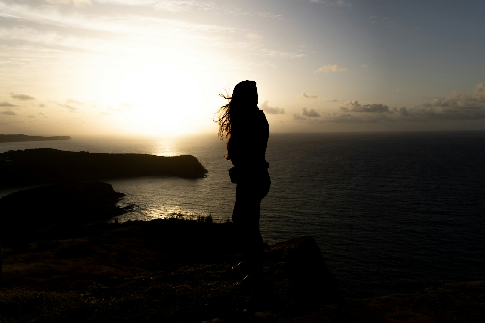 Silhouette of a person watching the sunset over the ocean.