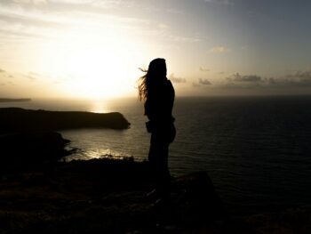 Silhouette of a person watching the sunset over the ocean.