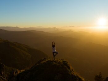 woman stretching on mountain top during sunrise